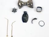 un nœud papillon, une bague, un bracelet et d'autres bijoux disposés sur une surface blanche
