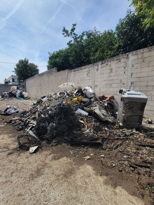a pile of garbage sitting on top of a dirt field next to a wall