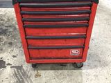 une boîte à outils rouge et noire posée sur un sol en béton