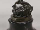 a bronze figurine of a woman sitting on top of a rock