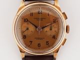 a gold watch with a brown face on a white surface