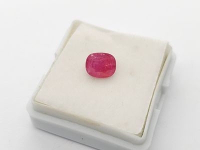an image of a red ruby stone sitting on a white surface