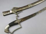 pair of silver plated swords with wooden handles and a black handle