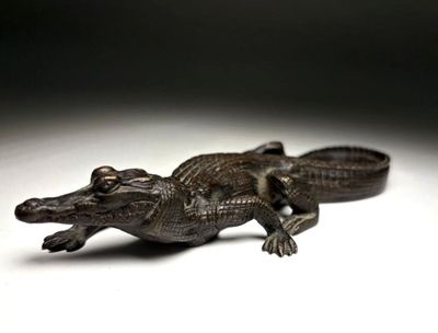 a statue of a small alligator on a white surface
