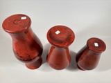 three red vases sitting next to each other on a white surface