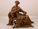statue en bronze représentant une femme assise sur une chaise avec un chien