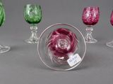 several different colored glass goblets and wine glasses on a gray surface