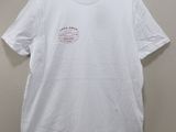 the white t - shirt is hanging on a hanger on a wall