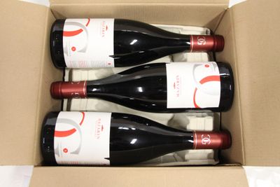 three bottles of red wine in a cardboard box on a table
