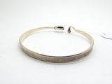 gros plan d'un bracelet en argent sur une surface blanche