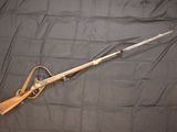 the rifle is laying on a black cloth with a wooden handle
