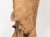 a clay sculpture of a man ' s head hanging on a wall