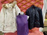 trois vestes et un gilet exposés devant un mur rose