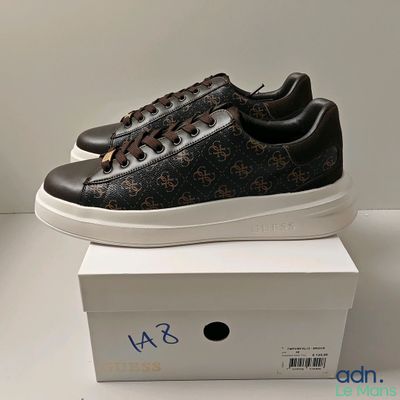 Les baskets noires et marron sont posées sur une boîte blanche.