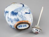 a blue and white vase with a small brush in it