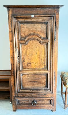 une grande armoire en bois dans une pièce où se trouve un banc