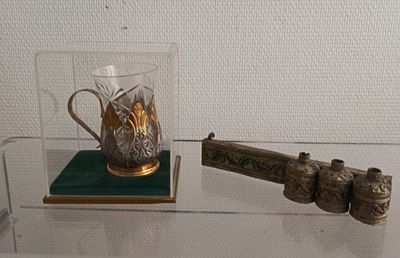 a glass display case with a gun and a glass cup on it