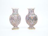 une paire de vases roses et verts posés sur une surface blanche