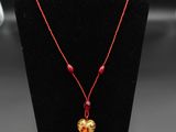 un collier orné d'une perle rouge et d'un cœur doré