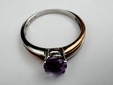 a close up of a ring with a purple stone on it