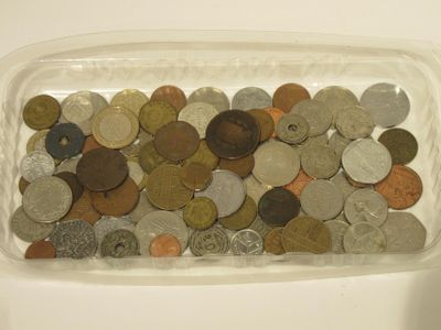 un récipient transparent rempli d'une multitude de pièces, posé sur une table