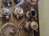 many silver teapots and cups on a wooden table