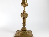 an antique brass candle holder on a wooden stand on a white background