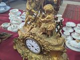 a gold clock sitting on a red table with a red table cloth