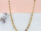 un collier à chaîne en or posé sur une surface en marbre