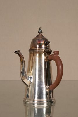 une cafetière en argent posée sur une table en verre