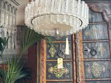 a chandelier in the middle of a room with a potted plant in it