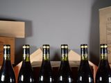 six bottles of wine are lined up in a row in front of a wooden crate