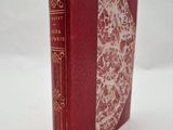 un vieux livre à la couverture rouge posé sur une table blanche