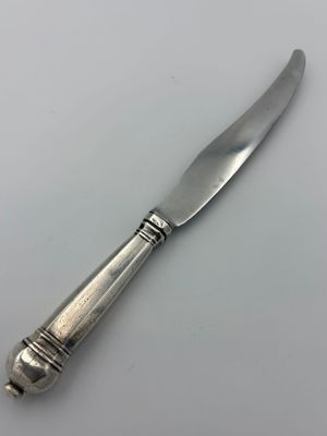 an antique silver plated knife on a white surface