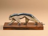 a metal sculpture of a cat on a wooden base