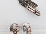 two pieces of silver and gold jewelry on a white surface