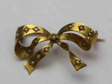 broche en forme de nœud ornée de perles et d'étoiles sur un fond blanc