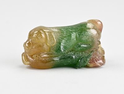 une figurine verte et jaune représentant un chien, posée sur une surface blanche