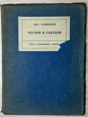 an old book with a blue cover sitting on top of a wooden table