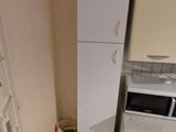 une petite cuisine avec un réfrigérateur blanc et des placards blancs