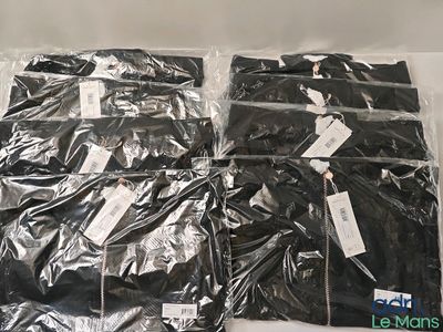quatre sacs contenant des vêtements noirs posés sur une surface blanche