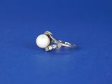 a close up of a white pearl and diamond ring on a blue background