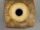 an image of a gold vase with a black hole in the center