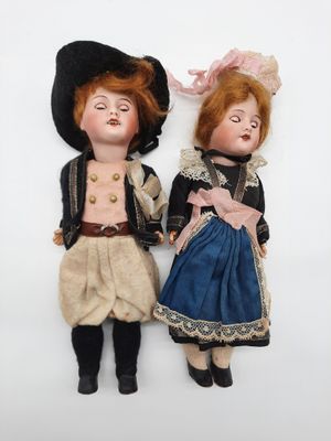 two dolls of a man and a woman are laying on a white surface