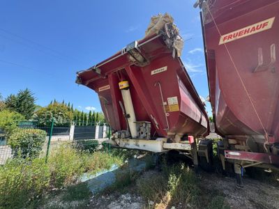 un camion-benne rouge garé sur le bord de la route