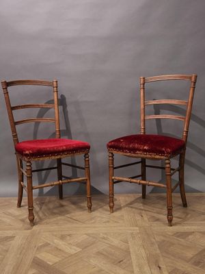 une paire de chaises en bois avec des coussins rembourrés rouges, devant un mur gris