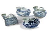 four pieces of blue and white porcelain items are arranged on a white surface