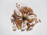 a gold and silver flower brooch on a white background