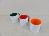 three different colored mugs sitting on a table