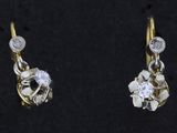 une paire de boucles d'oreilles en diamant et en or posées sur une surface noire